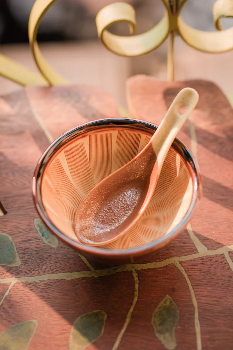 A ceramic spoon rests inside a red-lined bowl, revealing fine radial grooves and a stippled glaze